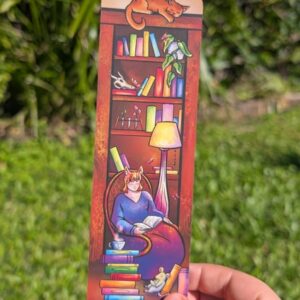 Cat lady reading sitting in frount of a cozy book shelf with artifacts on it. there is a mouse reading at hte ladys feet and a cat napping on top of the book shelf. in frount there is a stack of clourfull books with a cup of steeming tea on top. there is a a genral glowy soft cosy feel to the book mark with wood toans and pops of colour. there are 4 butterflys hiden flyinying around.