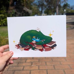 Laying on top of a pile of books is a sleeping curled green dragon and a baby blue dragon thats reading. There are sparkals too.
